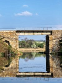 Arch bridge over river against sky