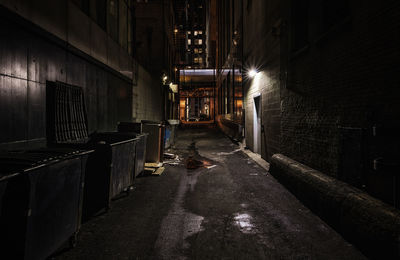 View of an empty corridor along buildings at night