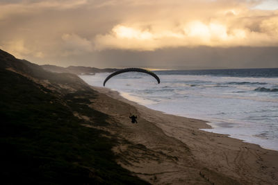 High angle view of man paragliding on beach during sunset