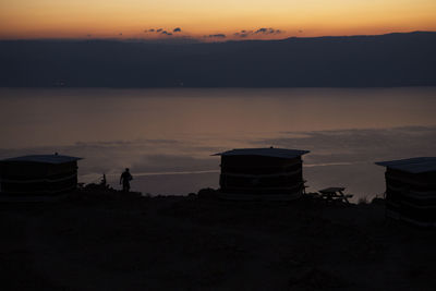 Silhouette people on beach against sky during sunset