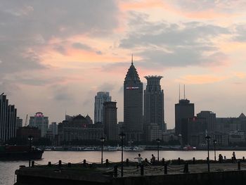 Buildings in city against cloudy sky during sunset