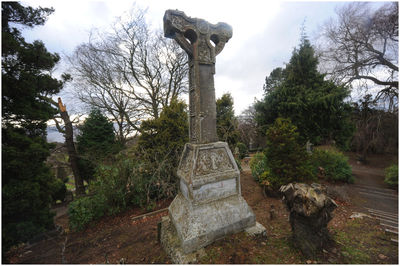 Stone sculpture in cemetery against sky