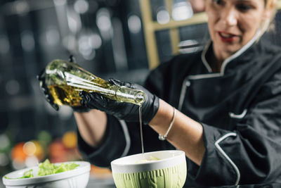 Chef pouring olive oil into a fresh green salad