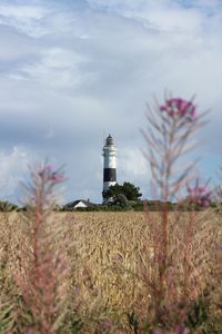 Lighthouse by agricultural field against sky