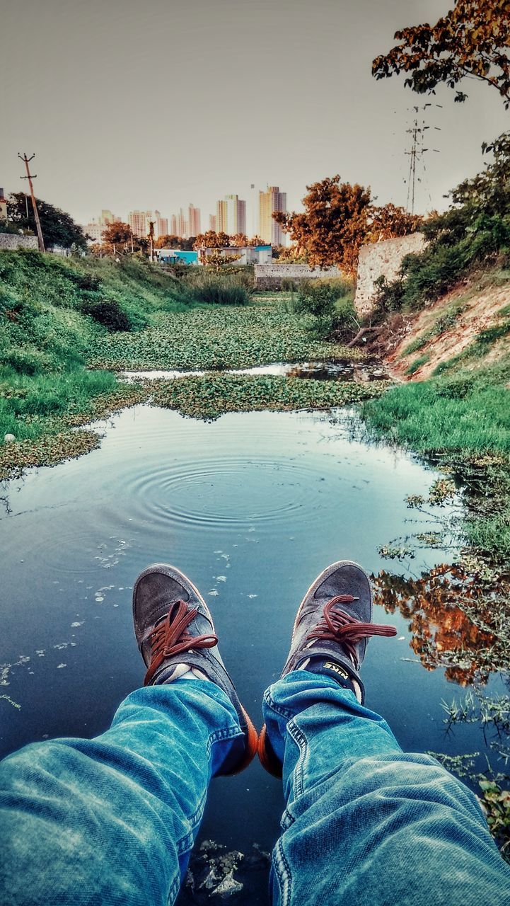 LOW SECTION OF MAN BY CANAL AGAINST SKY