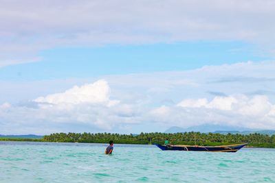 People in sea against sky