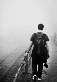 Rear view of man walking on road against sky