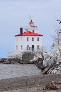 Lighthouse by sea against sky