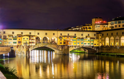 Arch bridge over river in city at night