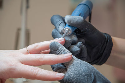 The manicurist grinds off the old coating with professional electric nail file.