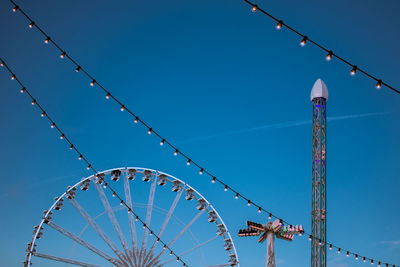 Low angle view of ferris wheel against clear blue sky