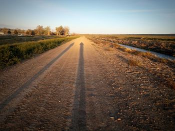 Road amidst field against clear sky