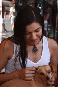 Smiling young woman with dog sitting outdoors