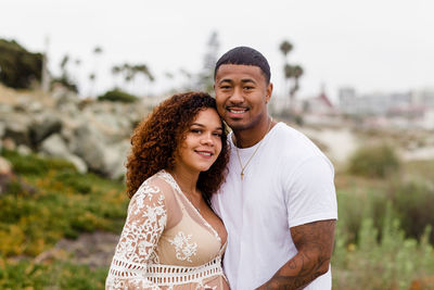 Mixed race couple smiling for camera on beach