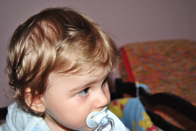 Cute baby boy sucking pacifier at home