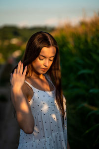 Young beautiful woman in white dress in corn field.