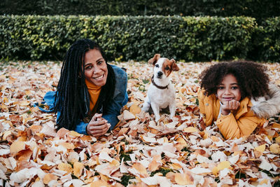 Happy woman with dog on leaves during autumn