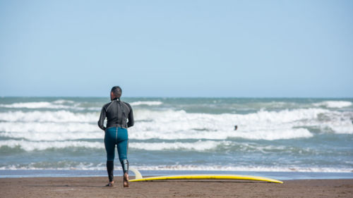 Rear view of man on beach against clear sky