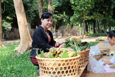 Happy young woman with fruits in basket on tree