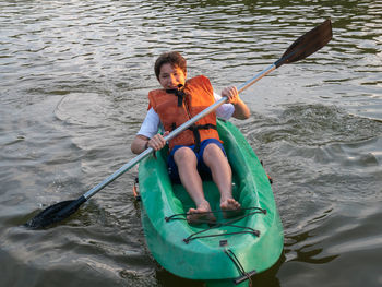 Young boy having fun kayaking on the lake at sunset.