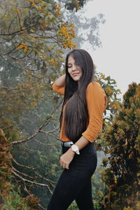 Smiling young woman standing in forest