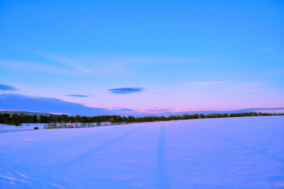 Snow covered landscape against blue sky