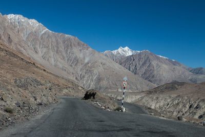 Man riding on road by mountain against sky