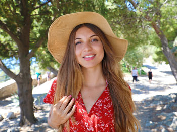 Portrait of smiling young woman wearing hat while standing on land