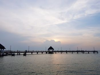 Pier over sea against sky during sunset