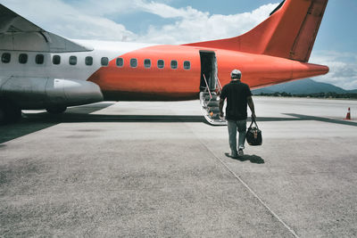 Rear view of man on airport runway against sky