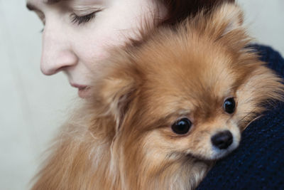 Close-up of young man with brown pomeranian dog at home