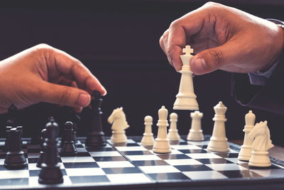 Cropped hands playing chess at table