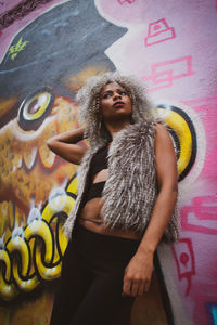 Young woman standing against graffiti wall