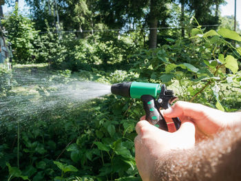 Hairy man's hands holding nozzle of watering hose