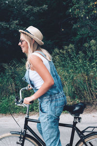 Side view of woman riding bicycle against trees in forest