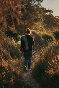 Rear view of women walking on forest path amidst trees