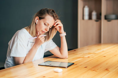 Young woman using mobile phone while sitting on table