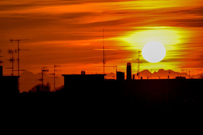 Silhouette buildings against orange sky