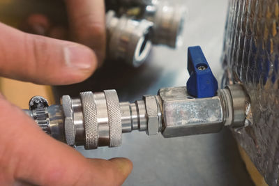 Cropped hands of plumber attaching pipe on metal