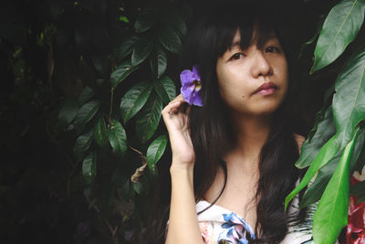 Portrait of young woman against plant