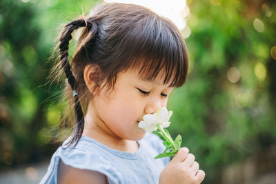 Close-up of cute girl holding flower outdoors
