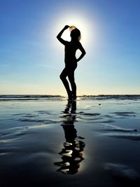 Silhouette woman posing at beach during sunny day