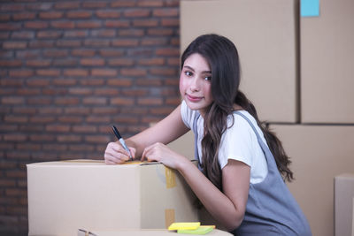 Portrait of woman sitting in box against wall