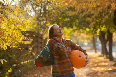 Side view of young woman standing against trees