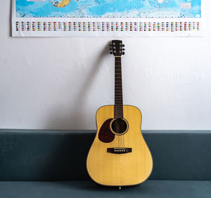 Close-up of guitar on table against wall at home