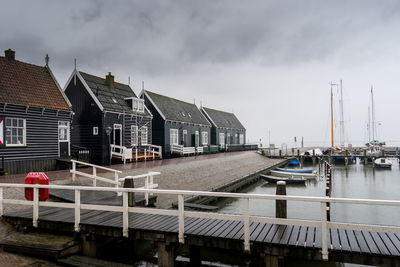 Sailboats in canal amidst buildings against sky