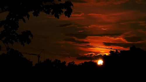 Low angle view of silhouette trees against dramatic sky at sunset