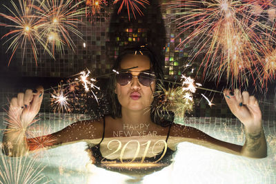 Digital composite image of woman with firework display in swimming pool