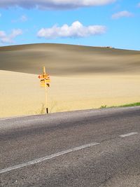 Road by desert against sky