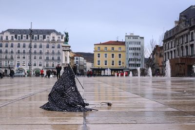 Broken umbrella on wet footpath against buildings in city